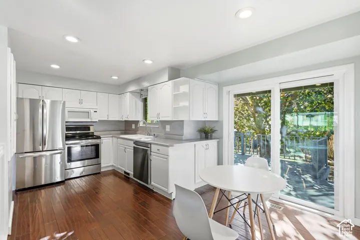 Kitchen featuring wood-finish flooring, white cabinetry, stainless steel appliances, and a sliding glass door