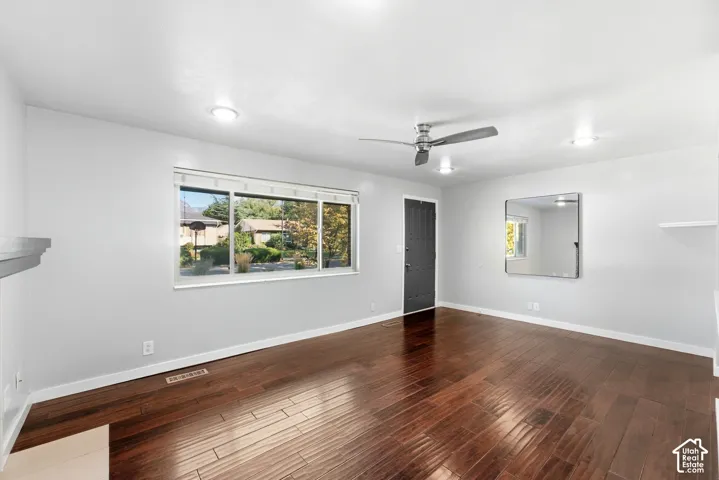 Rich wood-finish flooring, bright recessed lighting, and a modern ceiling fan