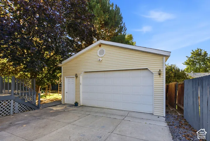 Detached garage with horizontal siding, a paneled garage door, and a side access door