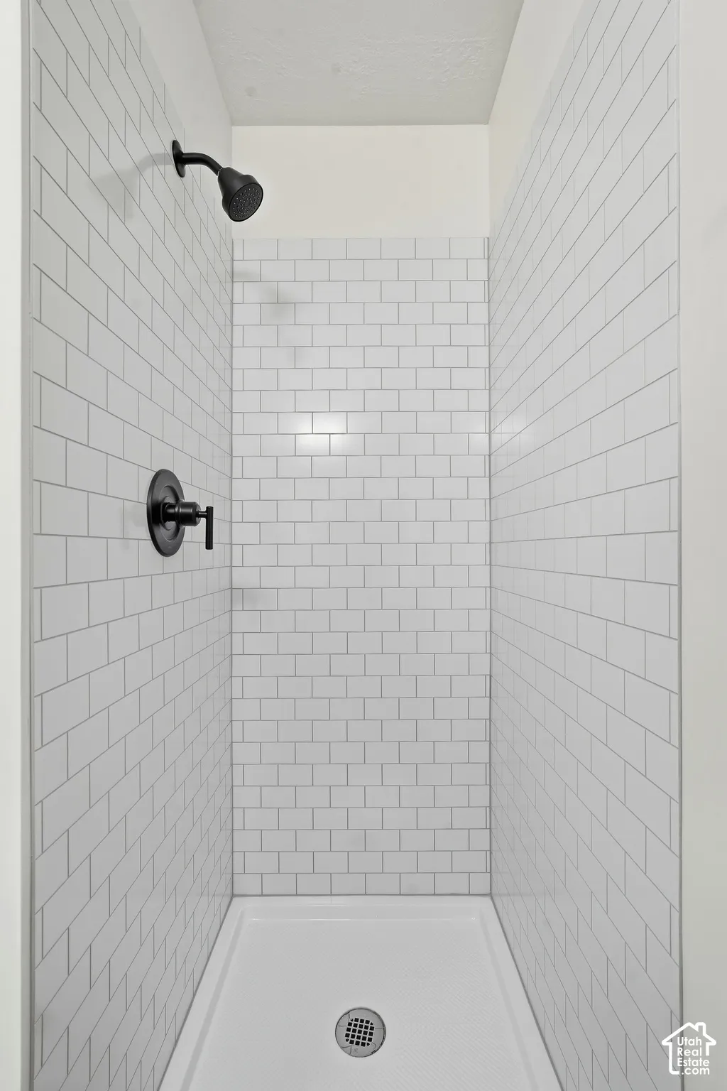 Walk-in shower with white subway tile surround, matte black showerhead, and matching matte black control handle