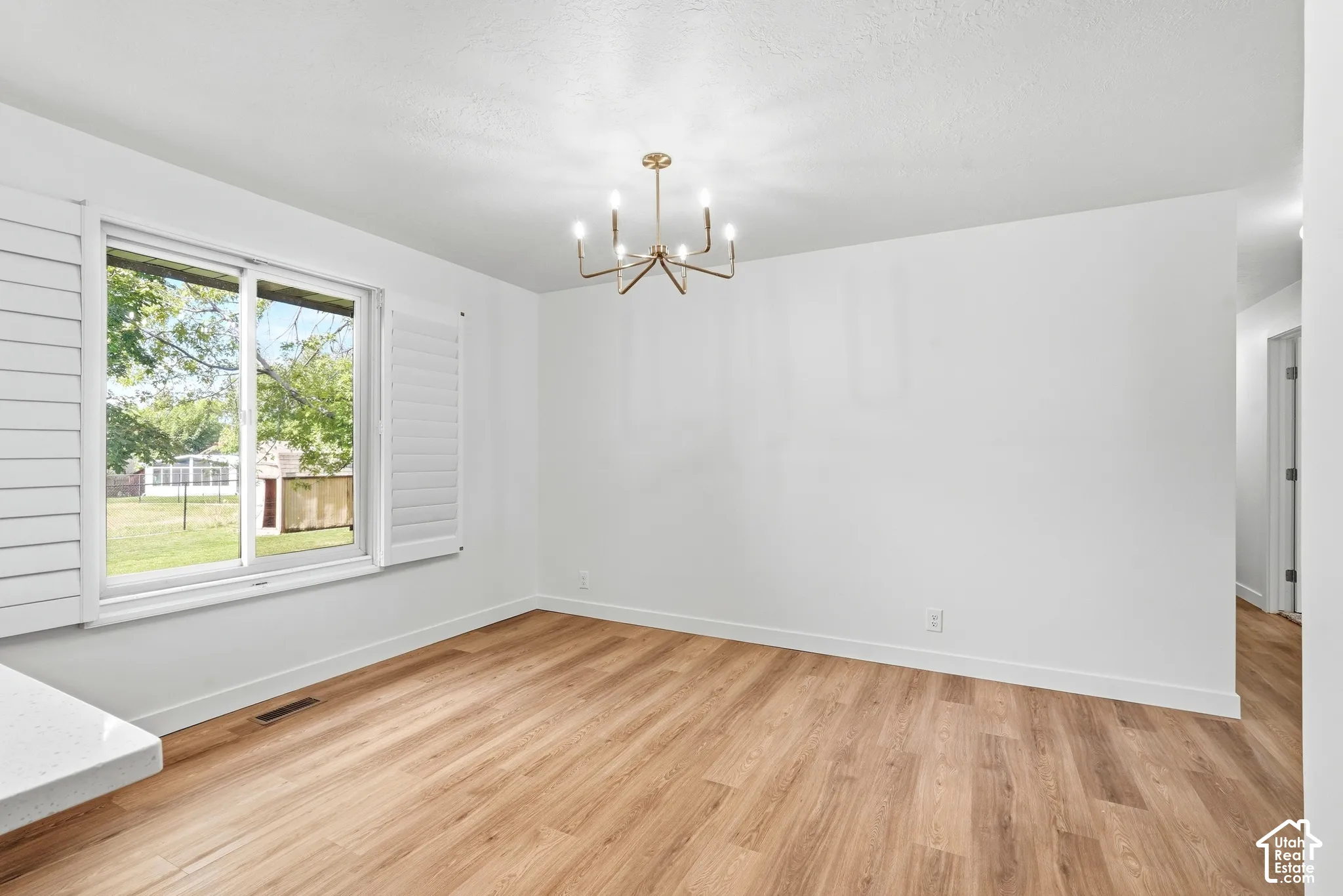 Wood-finish flooring, white walls, and a contemporary chandelier
