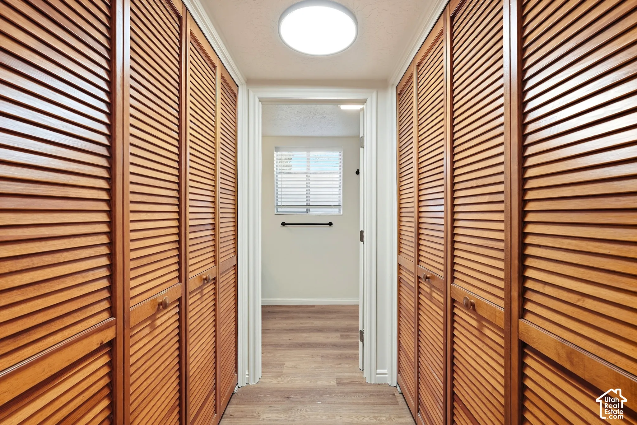 Wood-finish louvered bi-fold doors, recessed ceiling light, wood-finish flooring