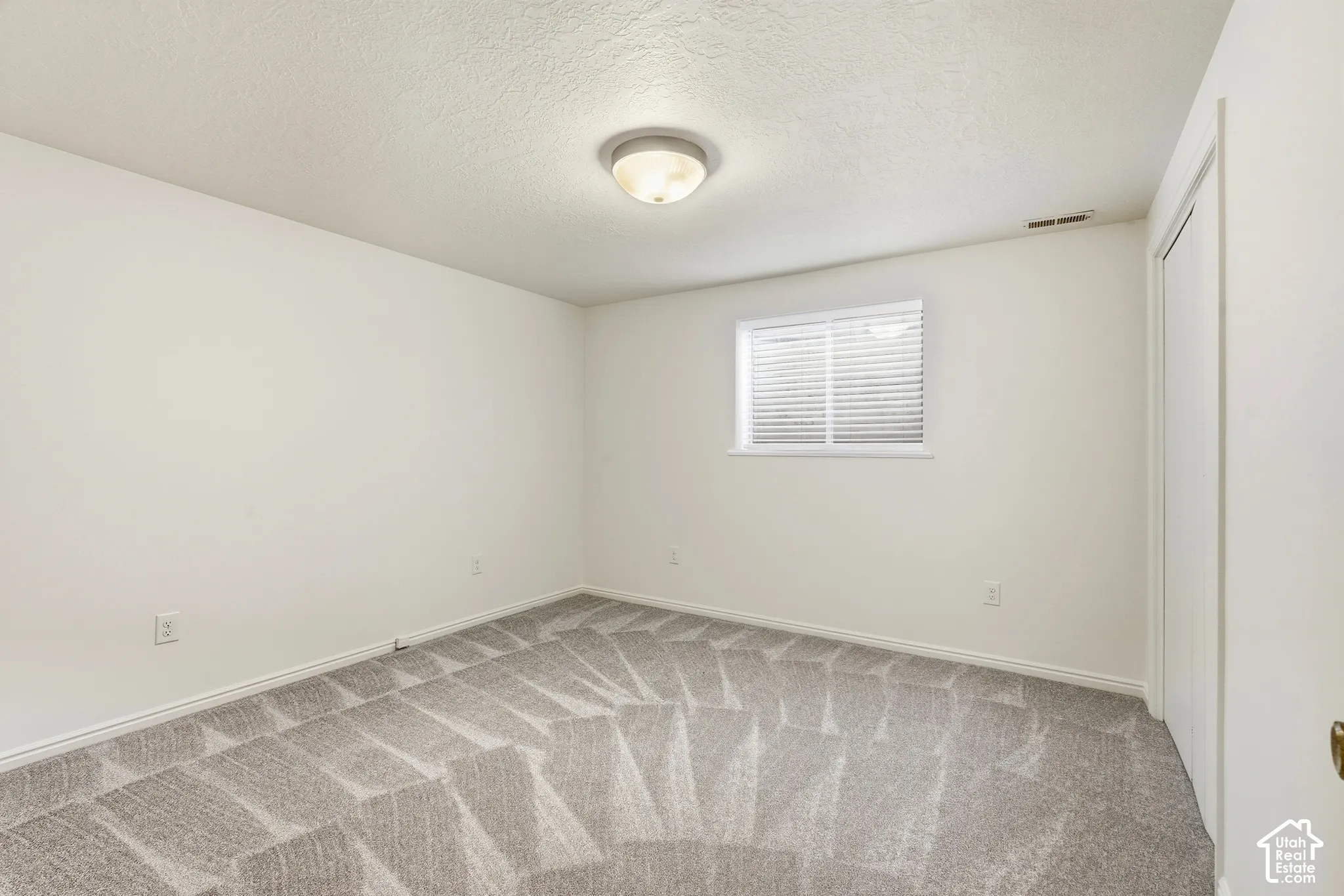 Light-toned walls with contrasting baseboards, patterned carpeting, and a flush-mount ceiling fixture