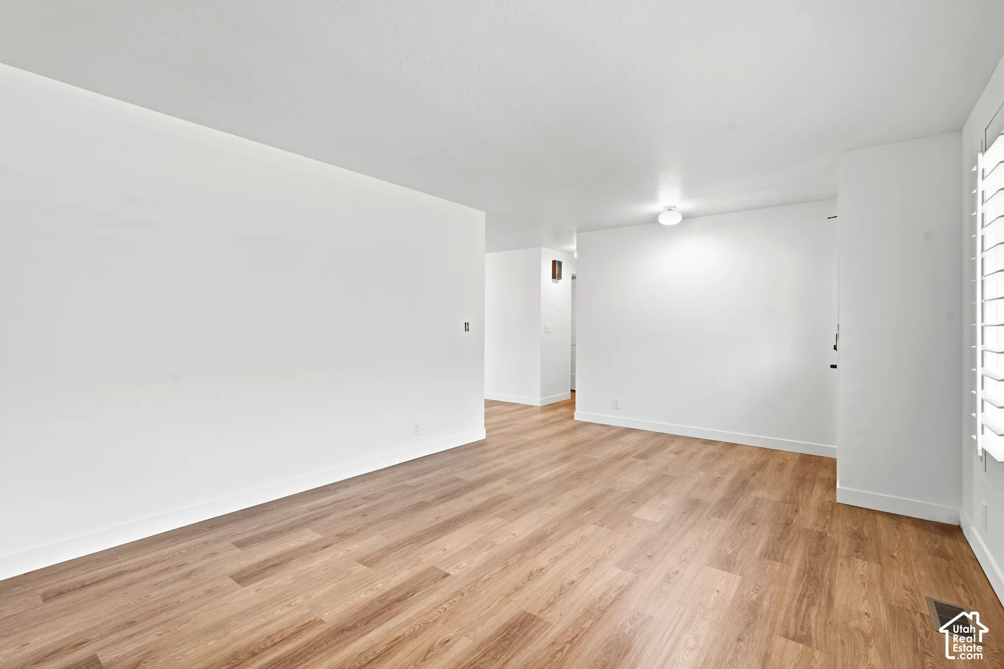 Formal Living room. Wood-finish flooring throughout, white painted walls, and a ceiling-mounted light fixture