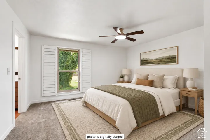 Neutral-toned carpeting, white plantation shutters, and a ceiling fan with integrated lighting