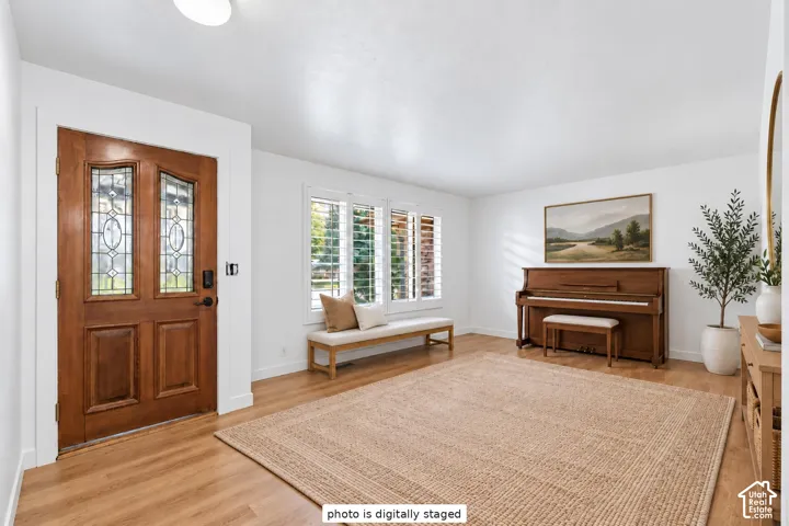 Entryway featuring a solid wood front door with decorative glass inserts, wood-finish flooring, and white plantation shutters