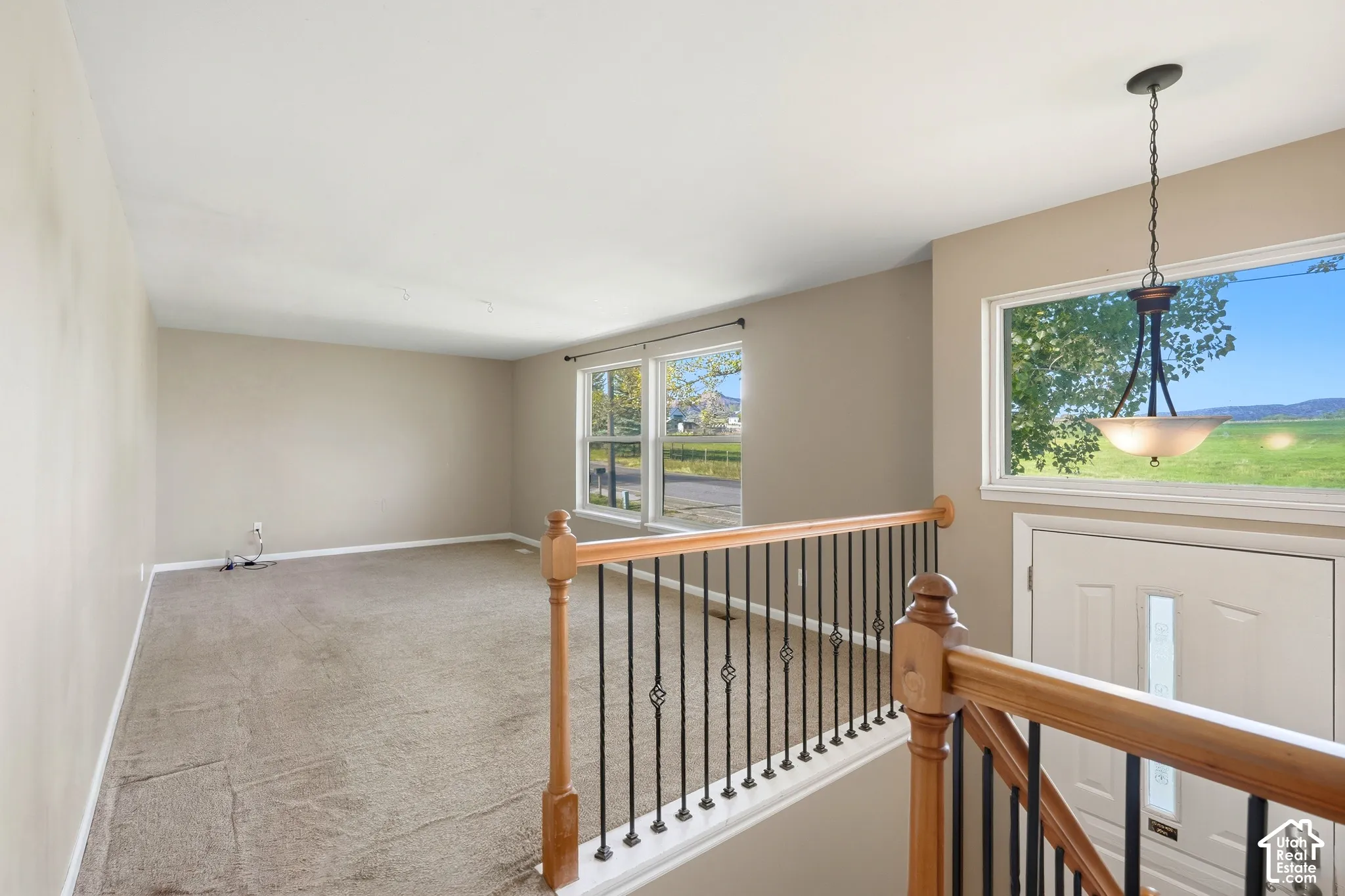 Upper level landing featuring wood railing with wrought iron balusters