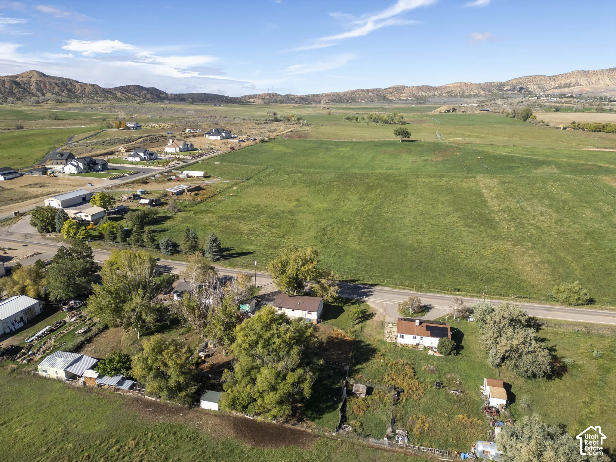 Expansive green fields with distant mountainous terrain under a clear sky