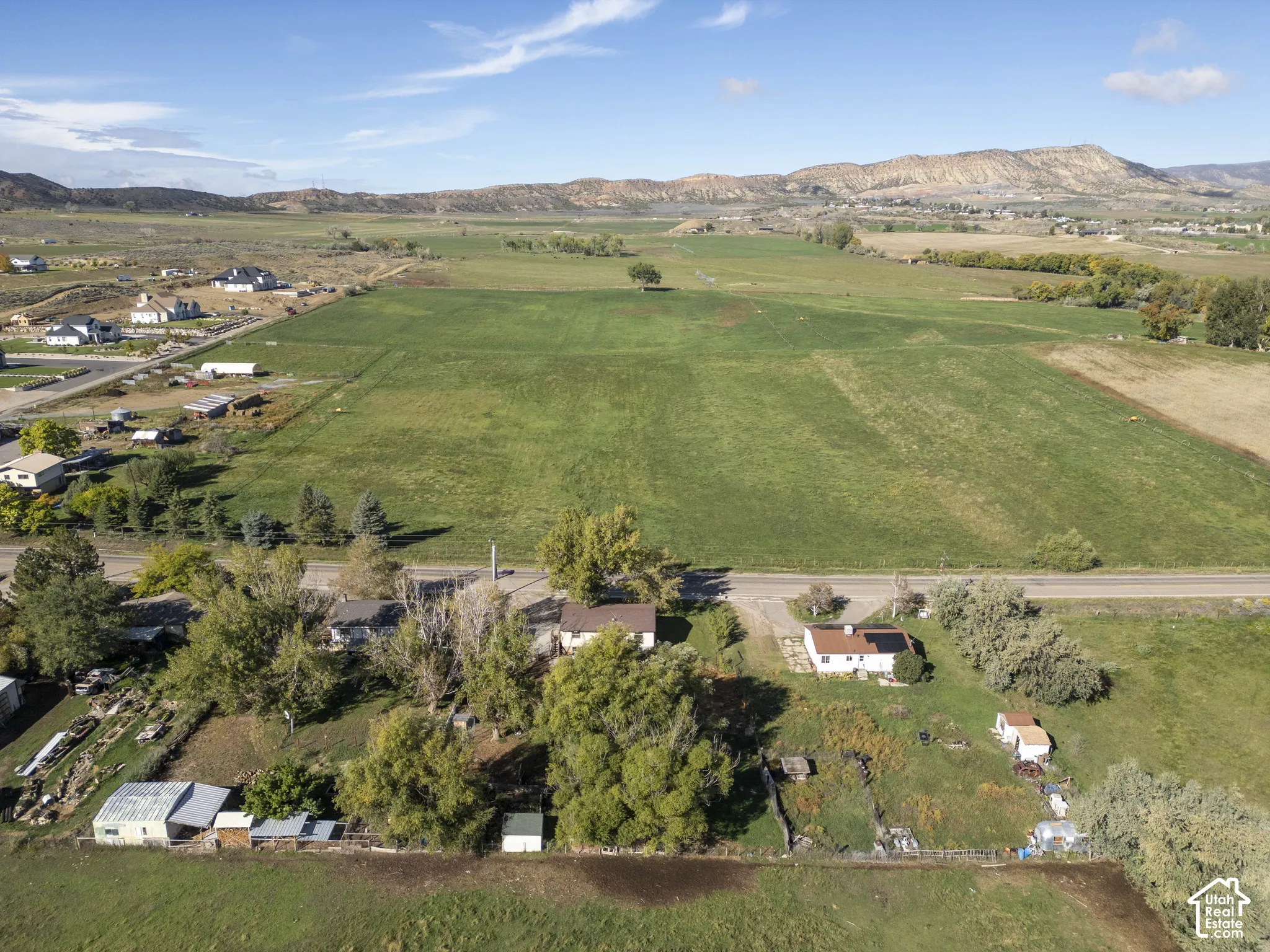 Expansive property featuring green fields, distant mountain ranges, and residential structures