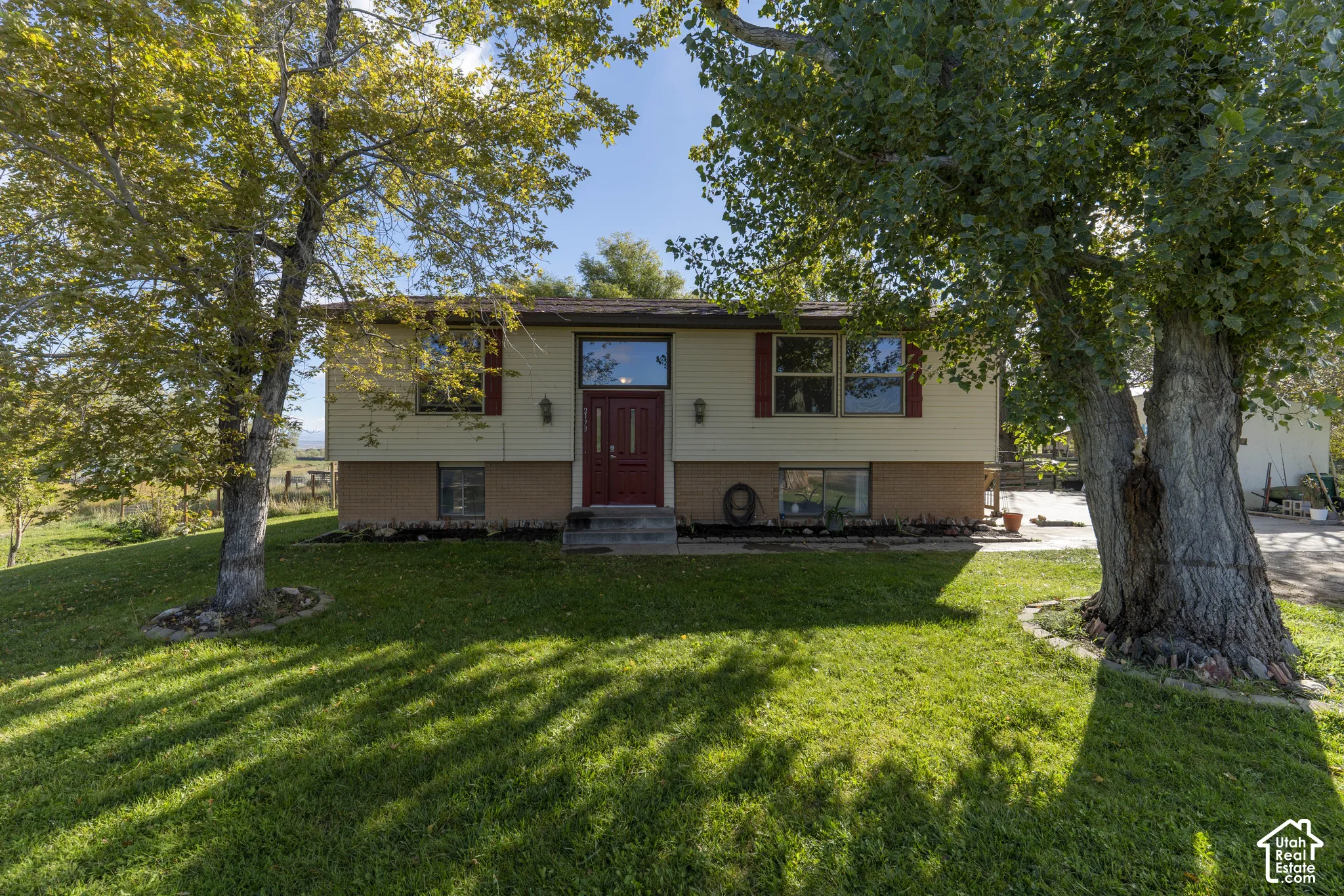 Split-level residence featuring a red entry door, horizontal siding, and a brick-finish foundation