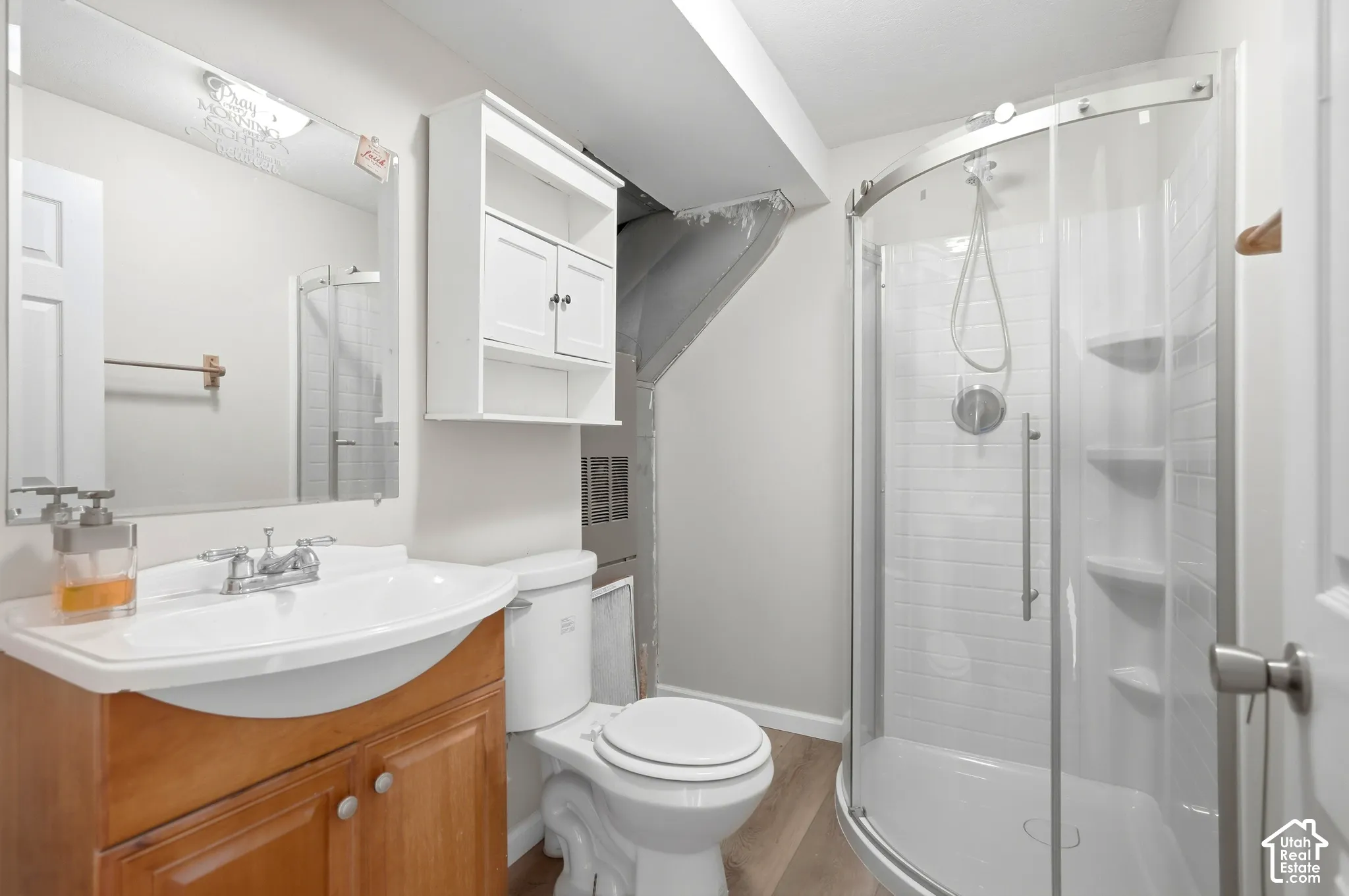 Vanity with wood-finish cabinetry, white ceramic sink, and chrome faucet
