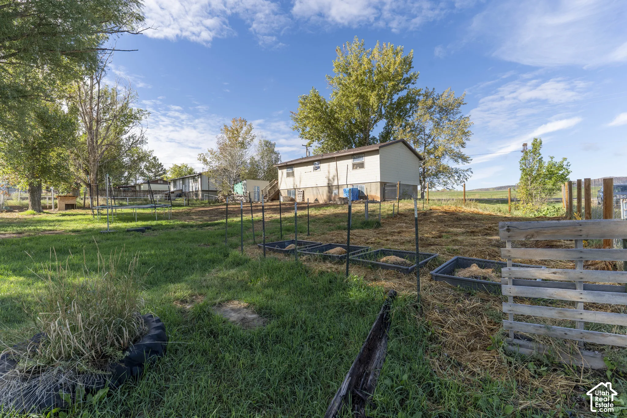Expansive lot featuring a structured garden area with raised beds and a mature tree line