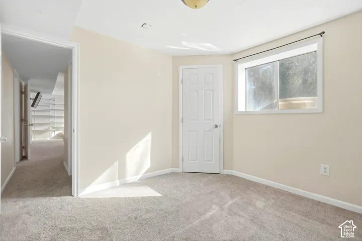 Light beige wall paint, light-colored carpeting, white trim, a white door, and a window with a dark curtain rod