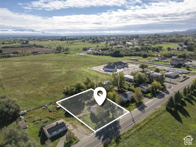Expansive green fields, paved road frontage, and established trees