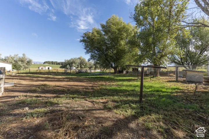 Expansive property featuring mature trees and open land, with a utility building visible in the background