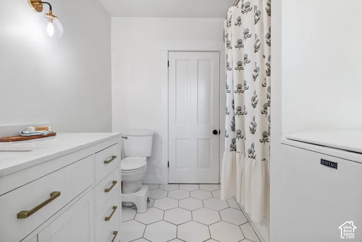 White vanity with brass hardware, white countertop, and hexagonal floor tiling