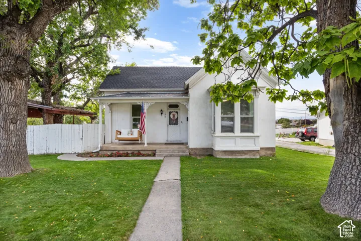 White exterior with a dark roof and a covered porch