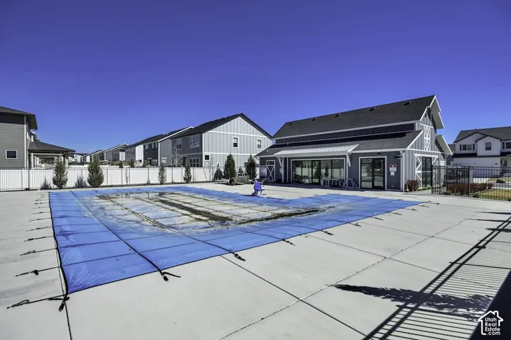 Resort-style pool with expansive concrete decking, complemented by a modern clubhouse featuring large windows and a covered entry