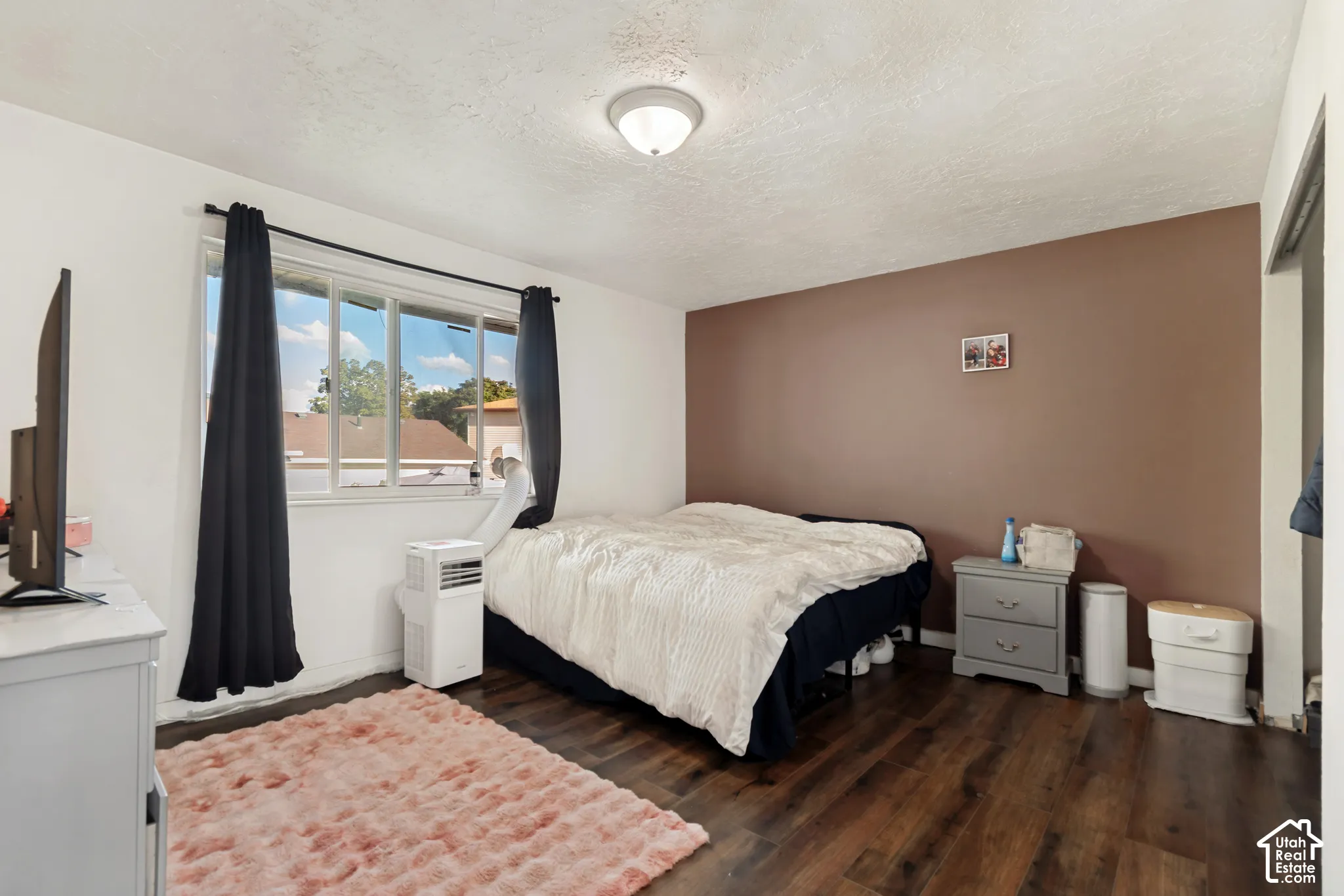Wood-finish flooring throughout, multiple windows, and a flush mount ceiling light fixture