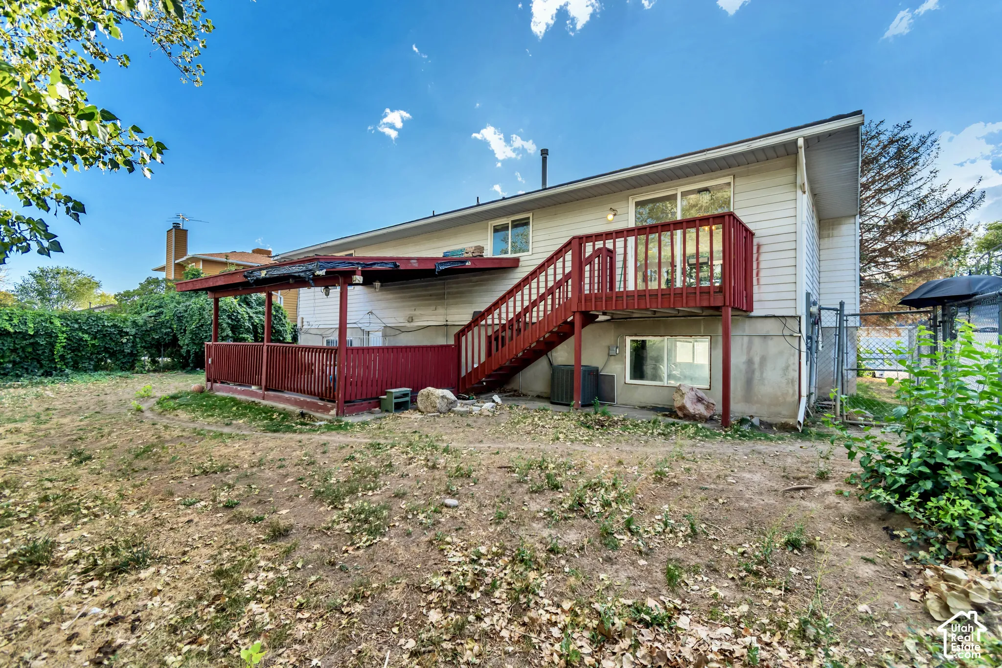 Rear exterior featuring a red-painted wood deck, covered patio, and white siding