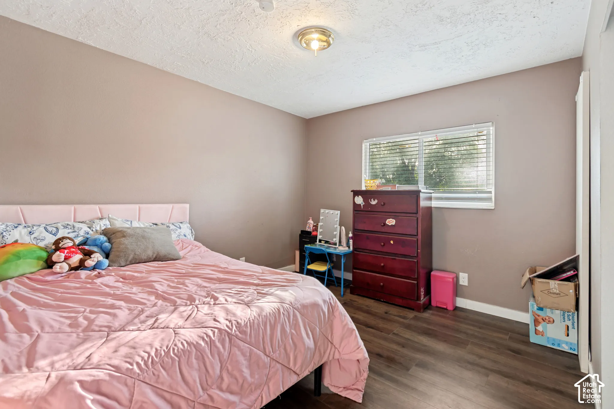 Wood-finish flooring, neutral wall color, and a window with blinds provide natural light