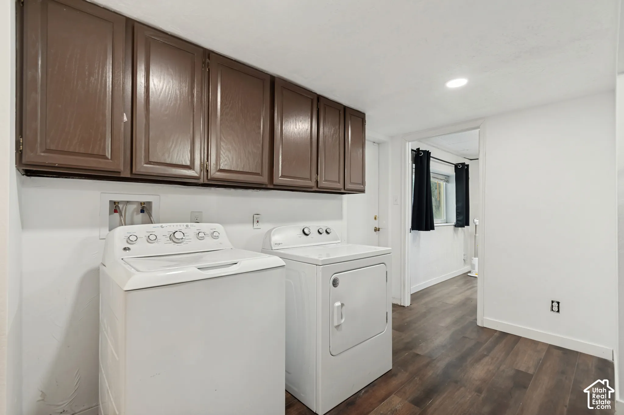 Wood-finish flooring with white walls and overhead cabinetry