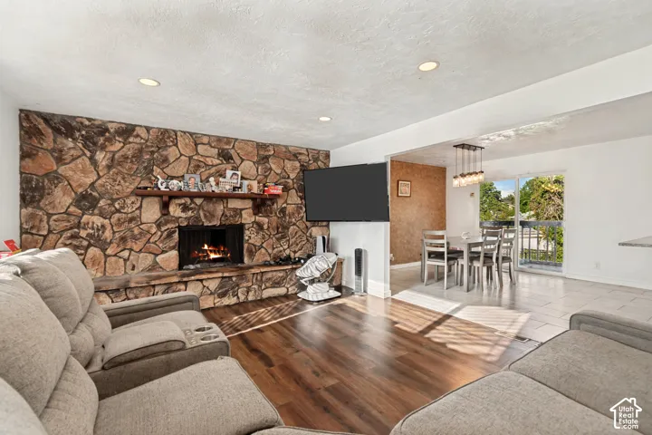 Stone-clad fireplace with wood mantel, wood-finish flooring, recessed lighting, and a sliding glass door to exterior