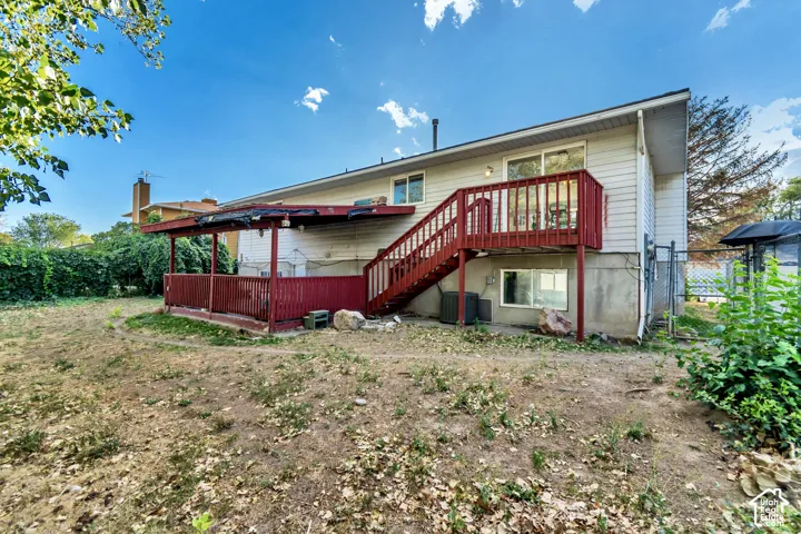 Rear exterior featuring a red-painted wood deck, covered patio, and white siding