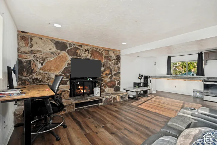 Stone accent wall with a built-in fireplace, wood-finish flooring, recessed lighting, and a built-in kitchen counter with a window