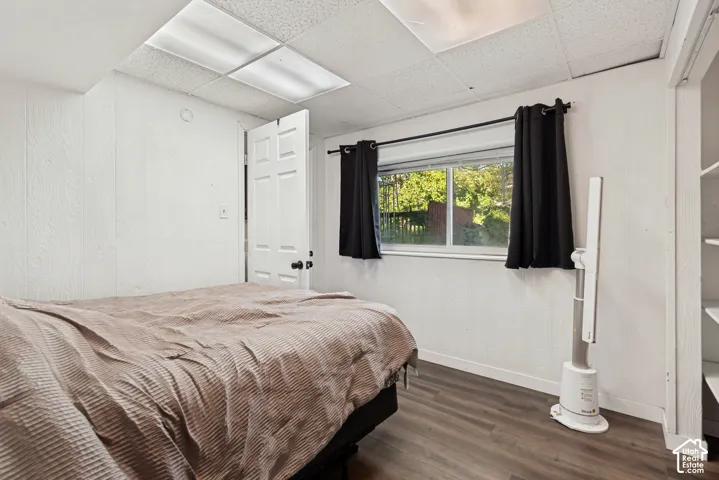 Wood-finish flooring, white paneling, and a drop ceiling with integrated lighting