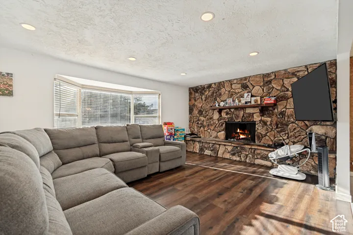 Wood-finish flooring, recessed lighting, and a stone-clad fireplace with a wood mantle