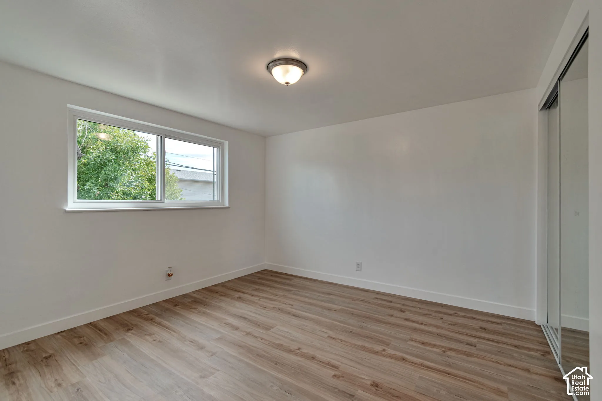 Recessed window with white trim, wood-finish flooring, white walls, and a ceiling-mounted light fixture