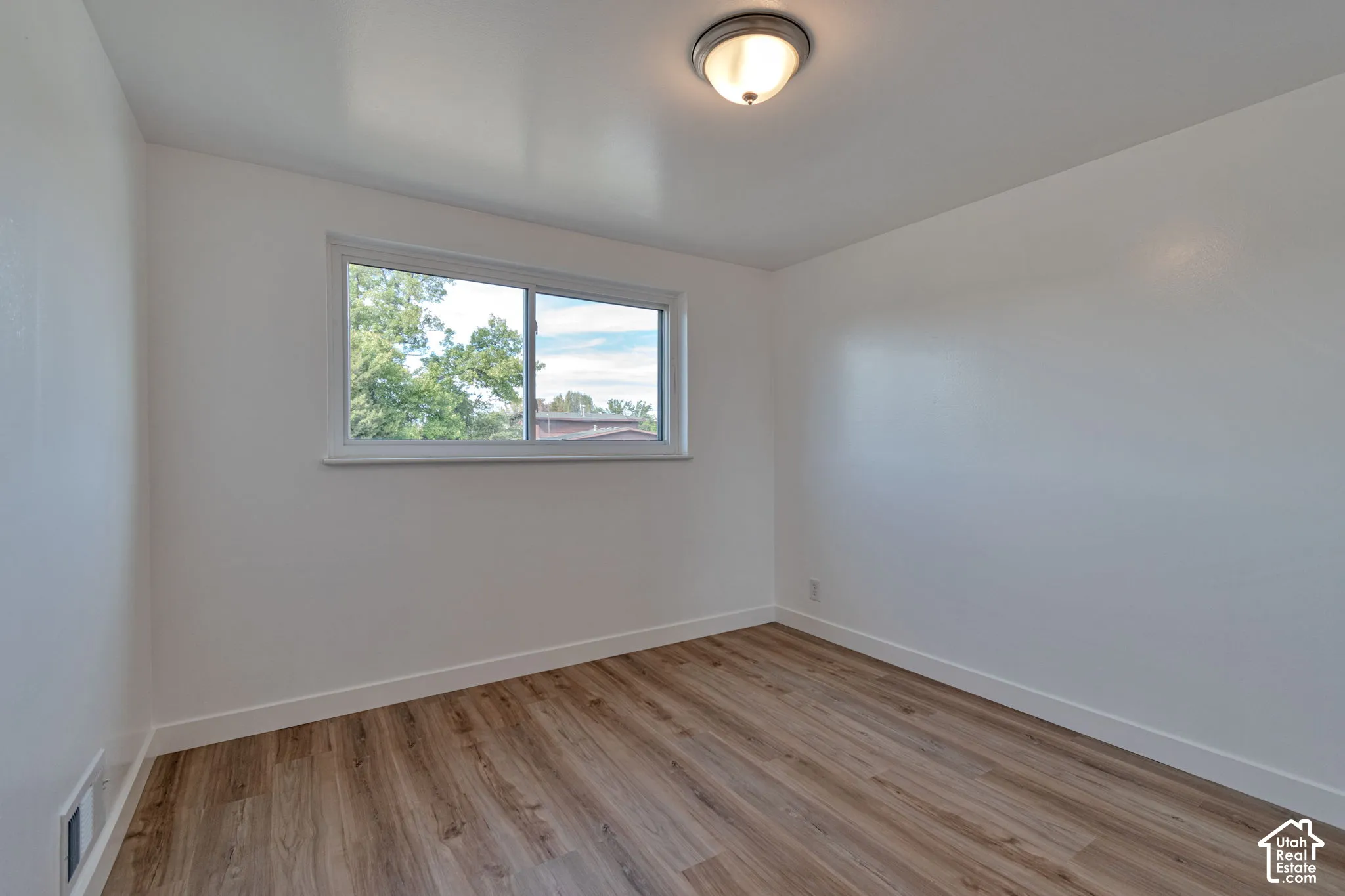 Wood-finish flooring, white walls, and a sliding window with white trim
