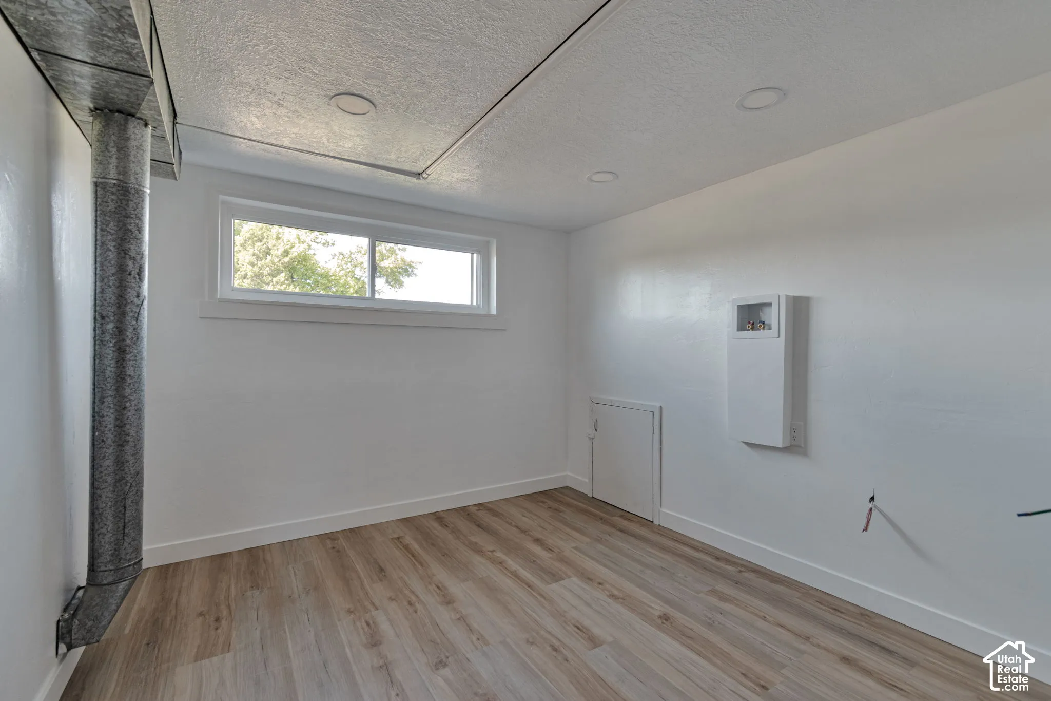 Wood-finish flooring, recessed ceiling lighting, and a white framed window