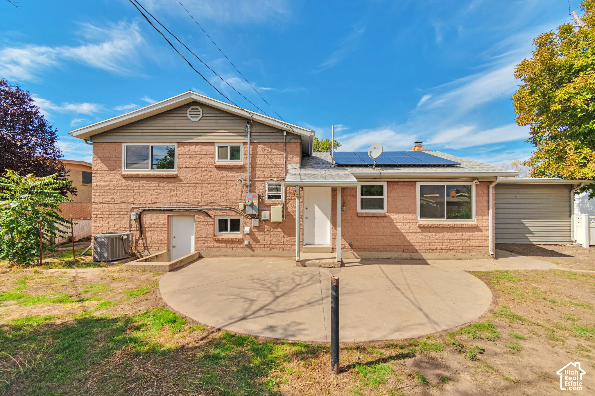 Brick exterior with attached garage, solar panels, and a concrete patio