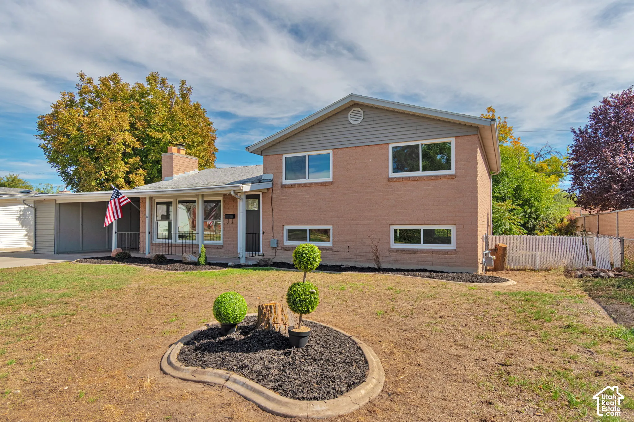 Brick exterior with gray siding accents, covered front entry, attached carport, and a front yard with manicured landscaping
