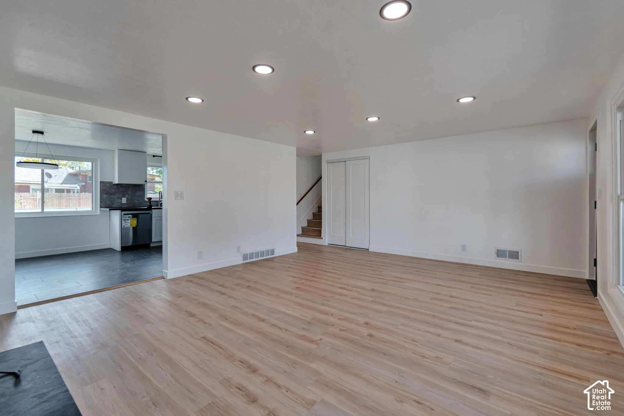 Recessed lighting, light wood-finish flooring, white walls, and a staircase with wood treads