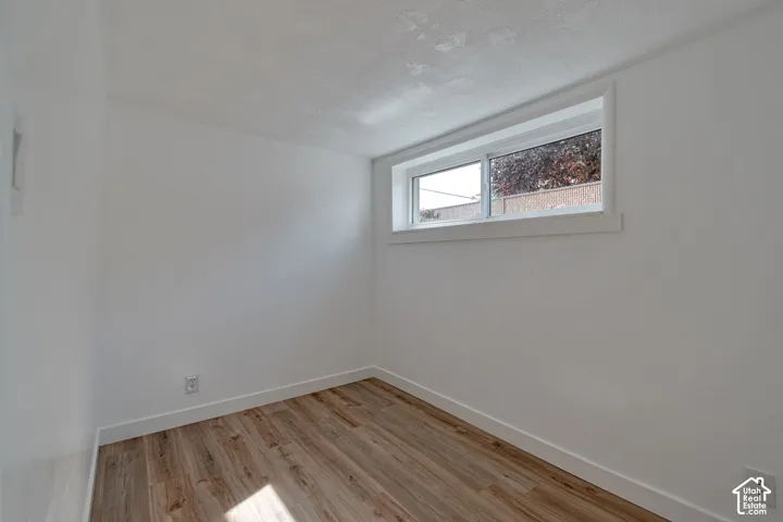 Wood-finish flooring, white walls, and a single window with white trim