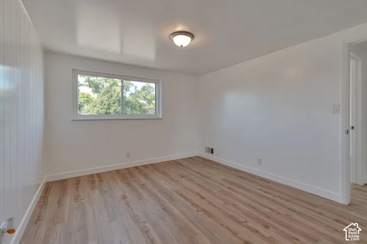 Wood-finish flooring, white walls, and a window providing natural illumination