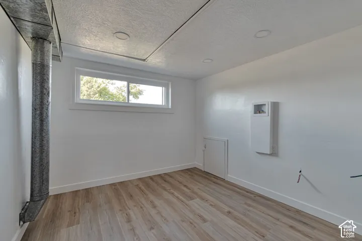 Wood-finish flooring, recessed ceiling lighting, and a white framed window