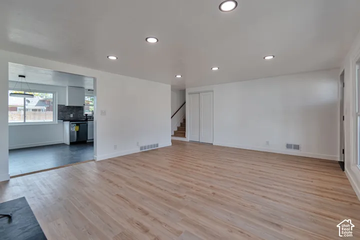 Recessed lighting, light wood-finish flooring, white walls, and a staircase with wood treads