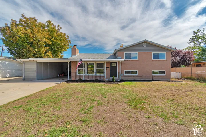 Brick-clad residence featuring a carport, detached garage, and a front yard with established landscaping