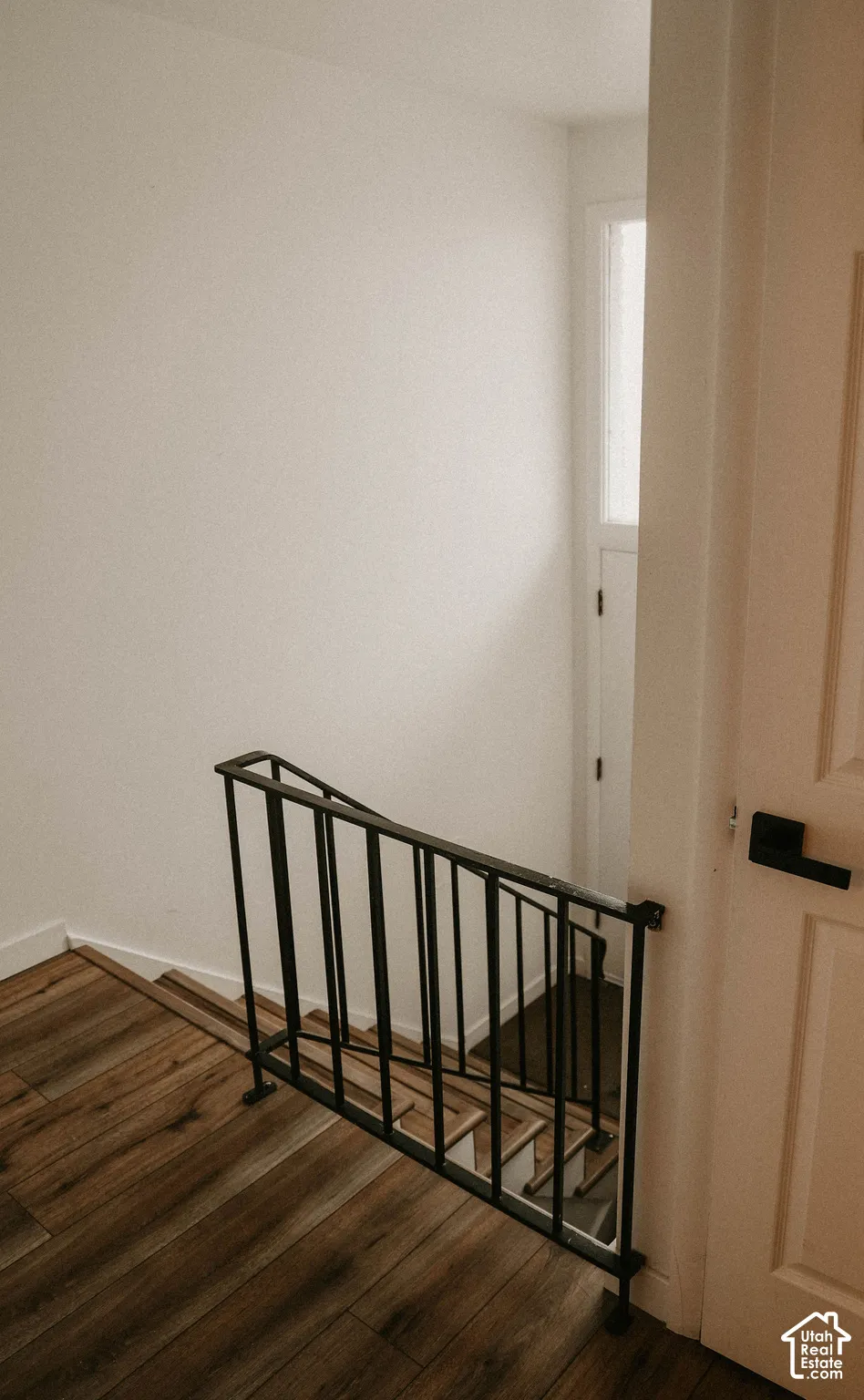 Wood-finish flooring, white walls, and a black metal railing