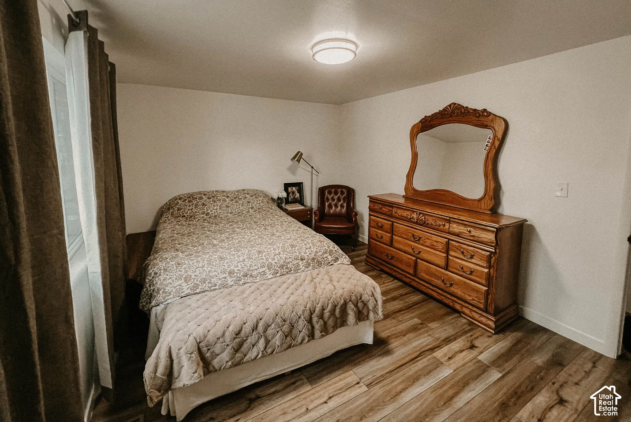 Wood-finish flooring, white walls, flush mount lighting, and a large window