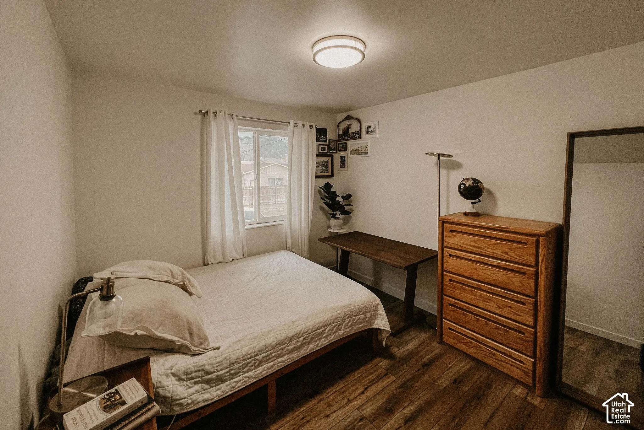Recessed window with white curtains, wood-finish flooring, and white painted walls