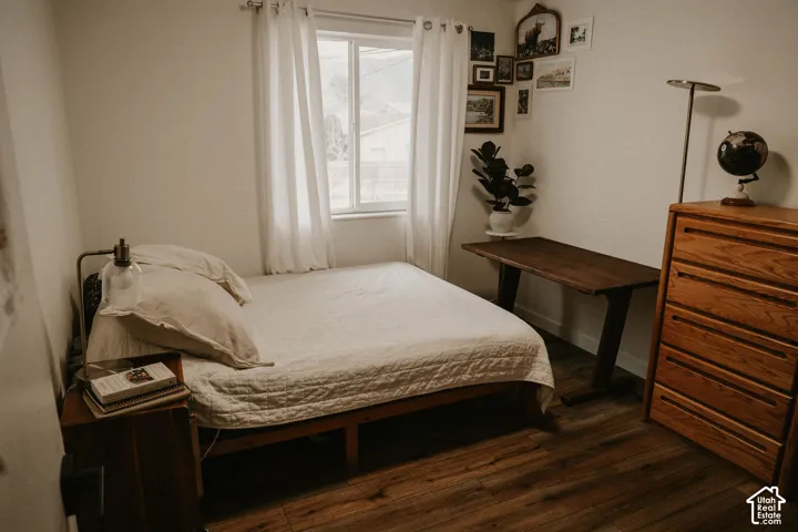 Wood-finish flooring, white walls, and a window with white curtains