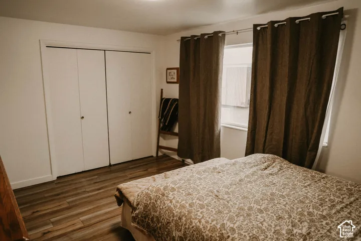 Bedroom featuring wood-finish flooring, a double window, and a built-in bifold closet