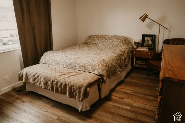 Wood-finish flooring, white walls, and a window with brown drapery