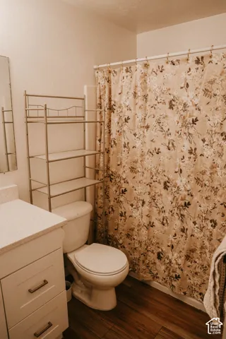 Wood-finish flooring with a white vanity featuring a light-colored countertop