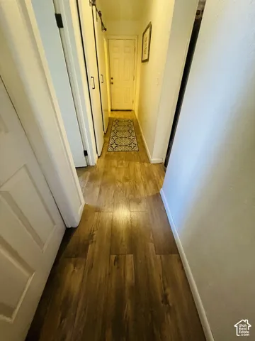 Wood-finish flooring throughout, white paneled interior doors, and modern barn door hardware